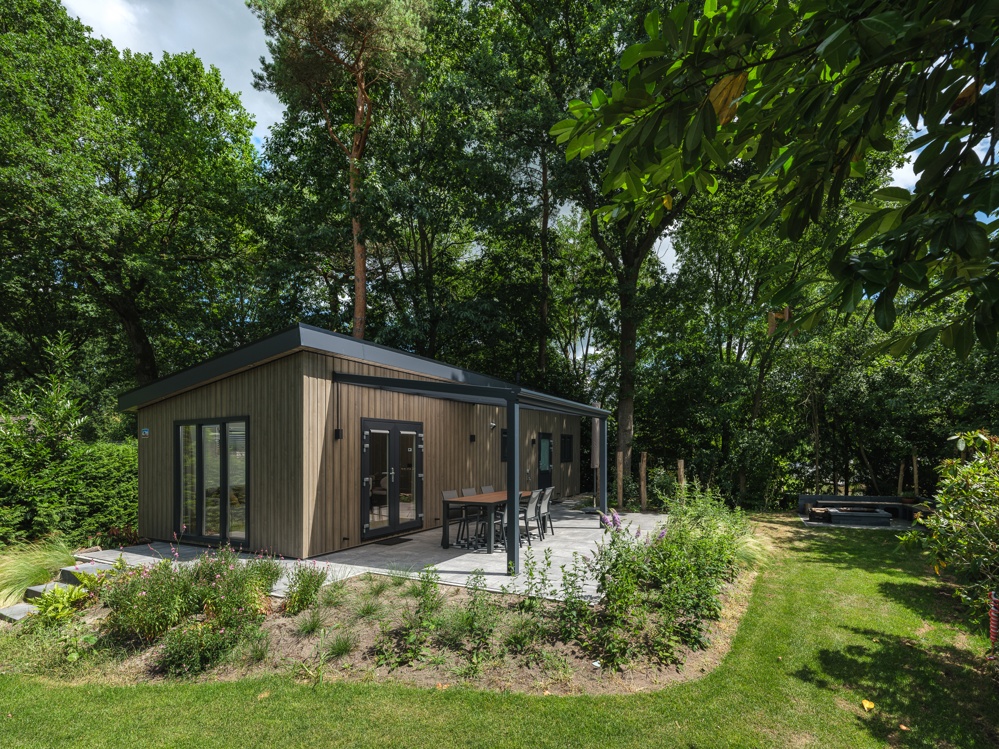 Geniet van een luxe vakantiewoning voor 4 personen in de bosrijke natuur van de Veluwe, compleet met moderne voorzieningen, airconditioning, een stijlvolle pergola én een zitlounge met buitenhaard vo..